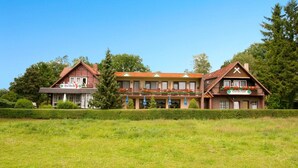 Un bâtiment traditionnel avec un toit rouge, de nombreuses fenêtres et une enseigne sur laquelle on peut lire « Berchdorf ».