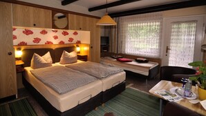Une chambre à coucher avec un lit double, des tables de chevet, un petit bureau, une chaise, une télévision et une fenêtre avec des rideaux.