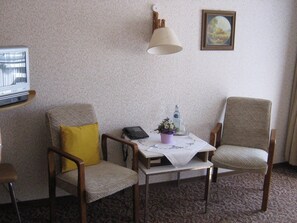 A room with two armchairs, a small table with a lamp, a television, and a framed picture on the wall. - Land-gut-hotel Landhaus Heidehof (Clenze)