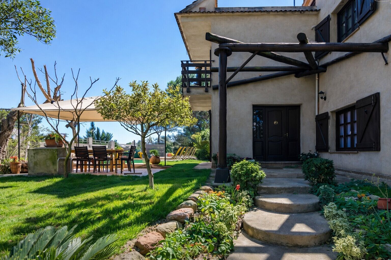 A house with a covered patio, a stone staircase, and a well-maintained garden.