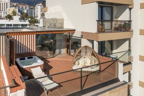 Un balcon doté d’un jacuzzi, de chaises longues et d’un fauteuil en osier.