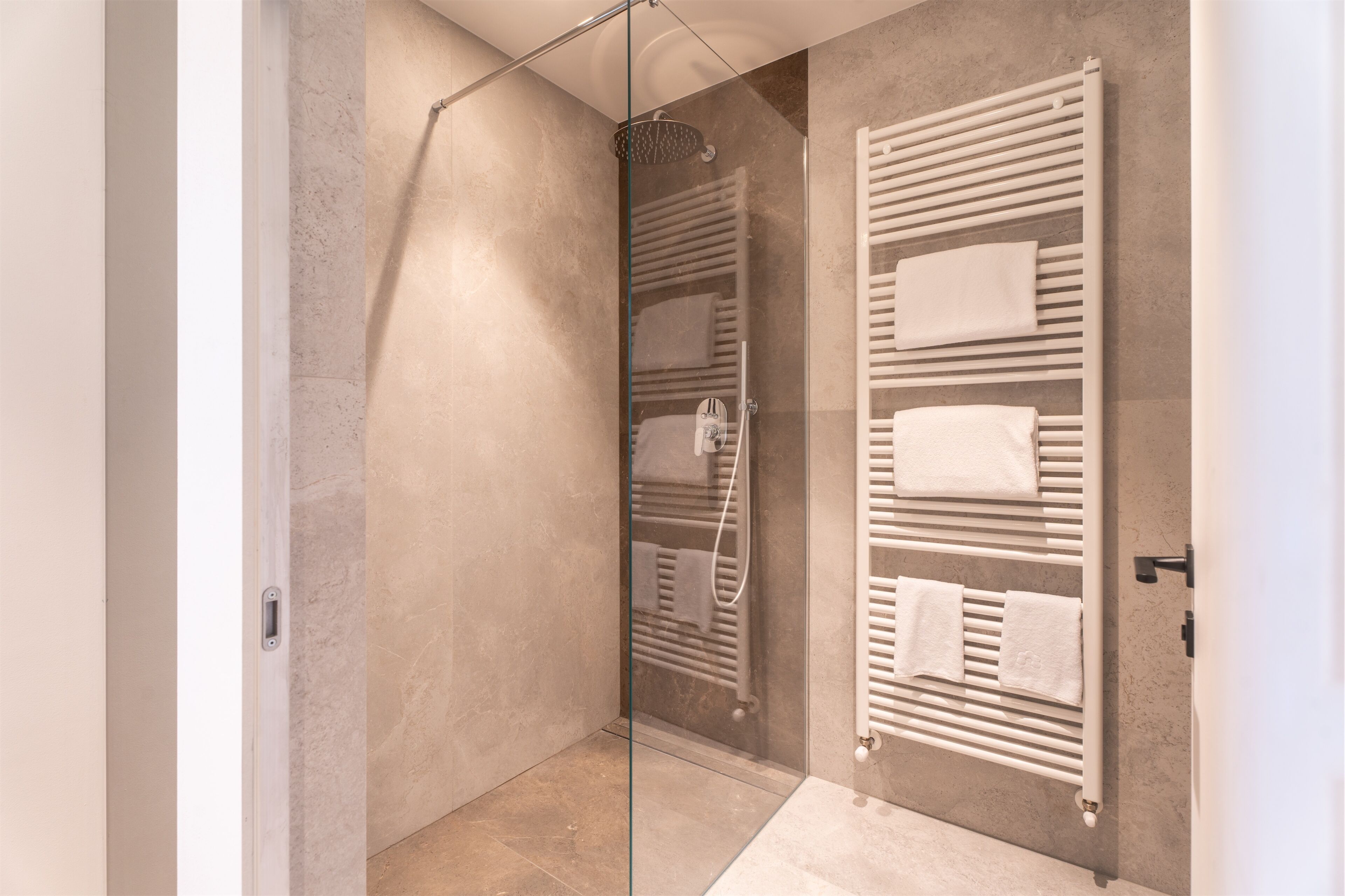 Un baño moderno con cabina de ducha de vidrio, toallero empotrado y un diseño minimalista y elegante.