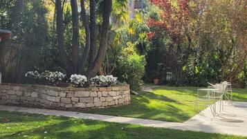 A well-maintained garden with a stone wall, a grassy lawn, and a metal chair.