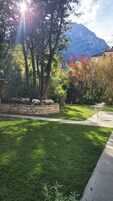 A well-maintained garden with a stone wall, a grassy lawn, and a metal chair.