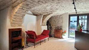 A cozy attic room with a red sofa, a wooden cabinet, and a stone wall. - Locanda Restel de Fer (Riva del Garda)