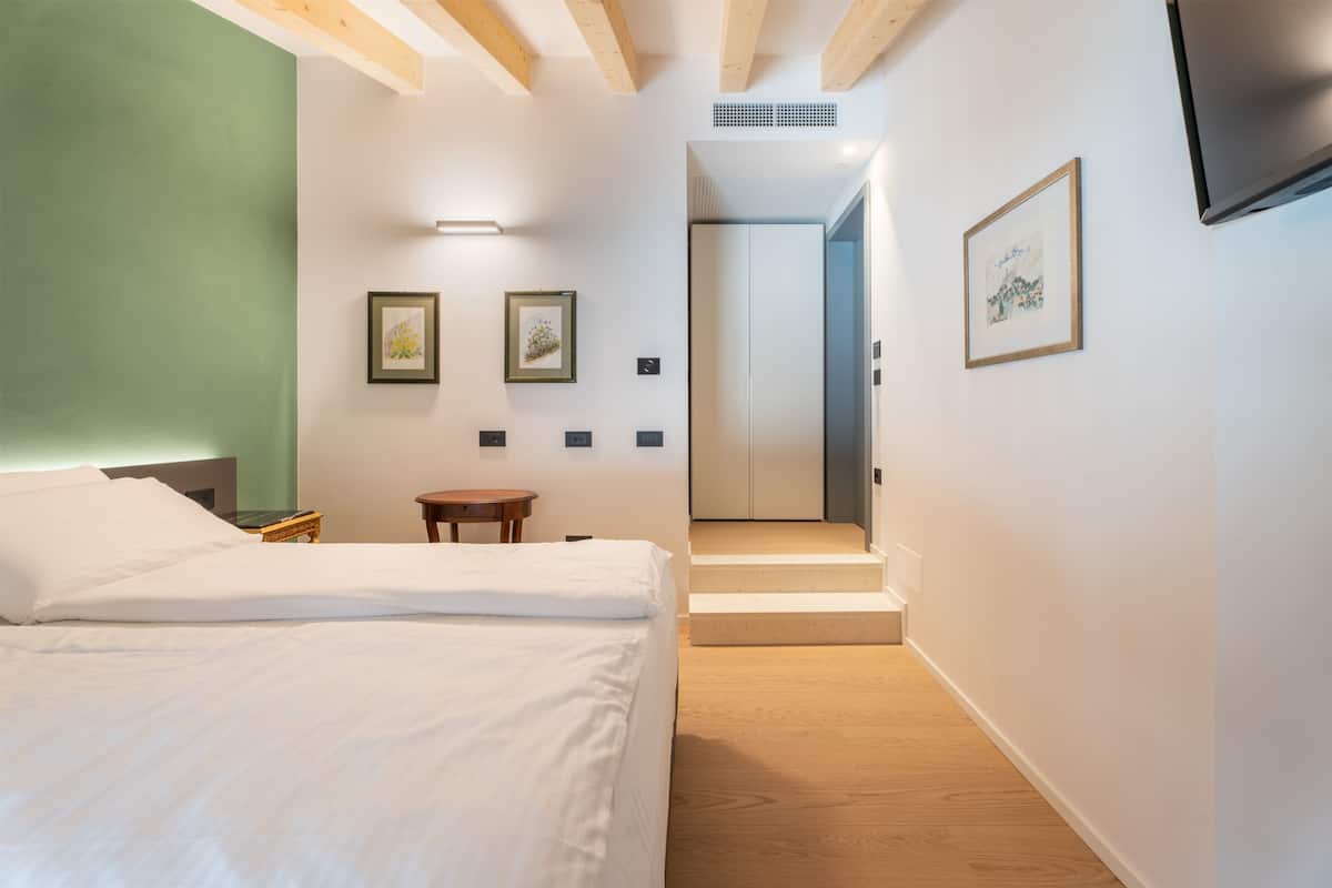 A modern hotel room with a bed, a small table, and a staircase leading to another room.