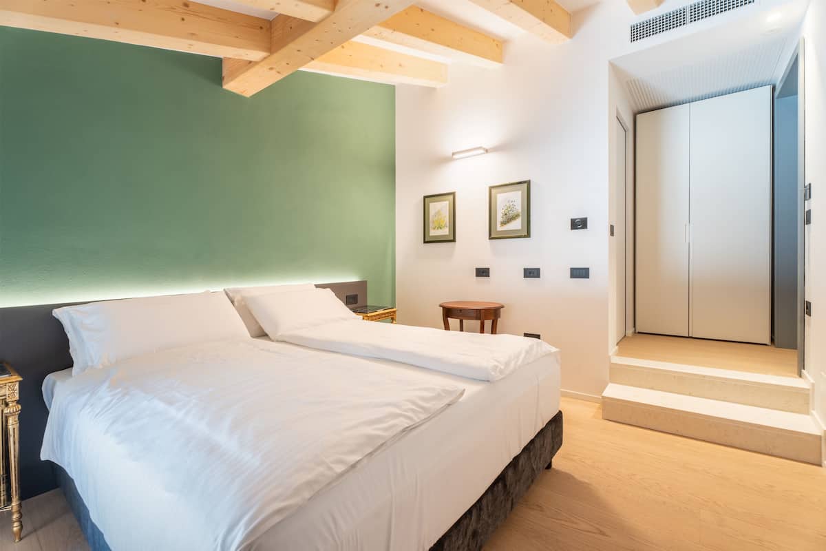 A bedroom with a bed, bedside tables, a small table, and a wardrobe.