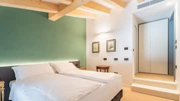 Un dormitorio con cama, mesitas de noche, una pequeña mesa y un armario.