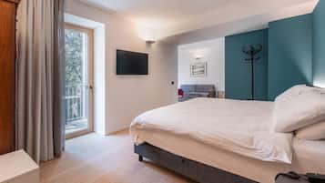 Un dormitorio con cama, televisor, perchero y balcón.