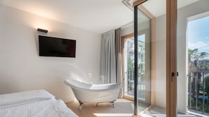 A modern bathroom with a freestanding bathtub, a large mirror, and a sliding glass door leading to a balcony. - Locanda Restel de Fer (Riva del Garda)