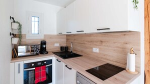 Een moderne keuken met witte kasten, een inbouwoven, een magnetron en een koffiezetapparaat.