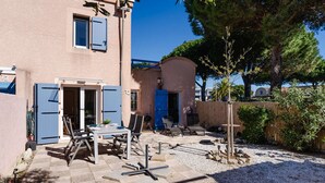 Een gebouw met twee verdiepingen, met een patio voorzien van tuinmeubilair en een barbecue.