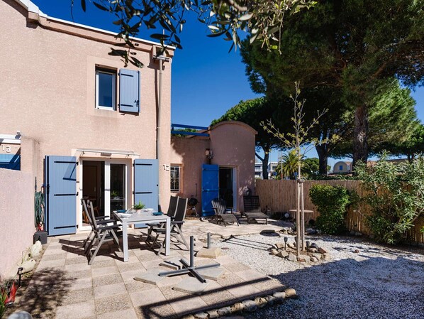 A two-story building with a patio area featuring outdoor furniture and a barbecue grill.