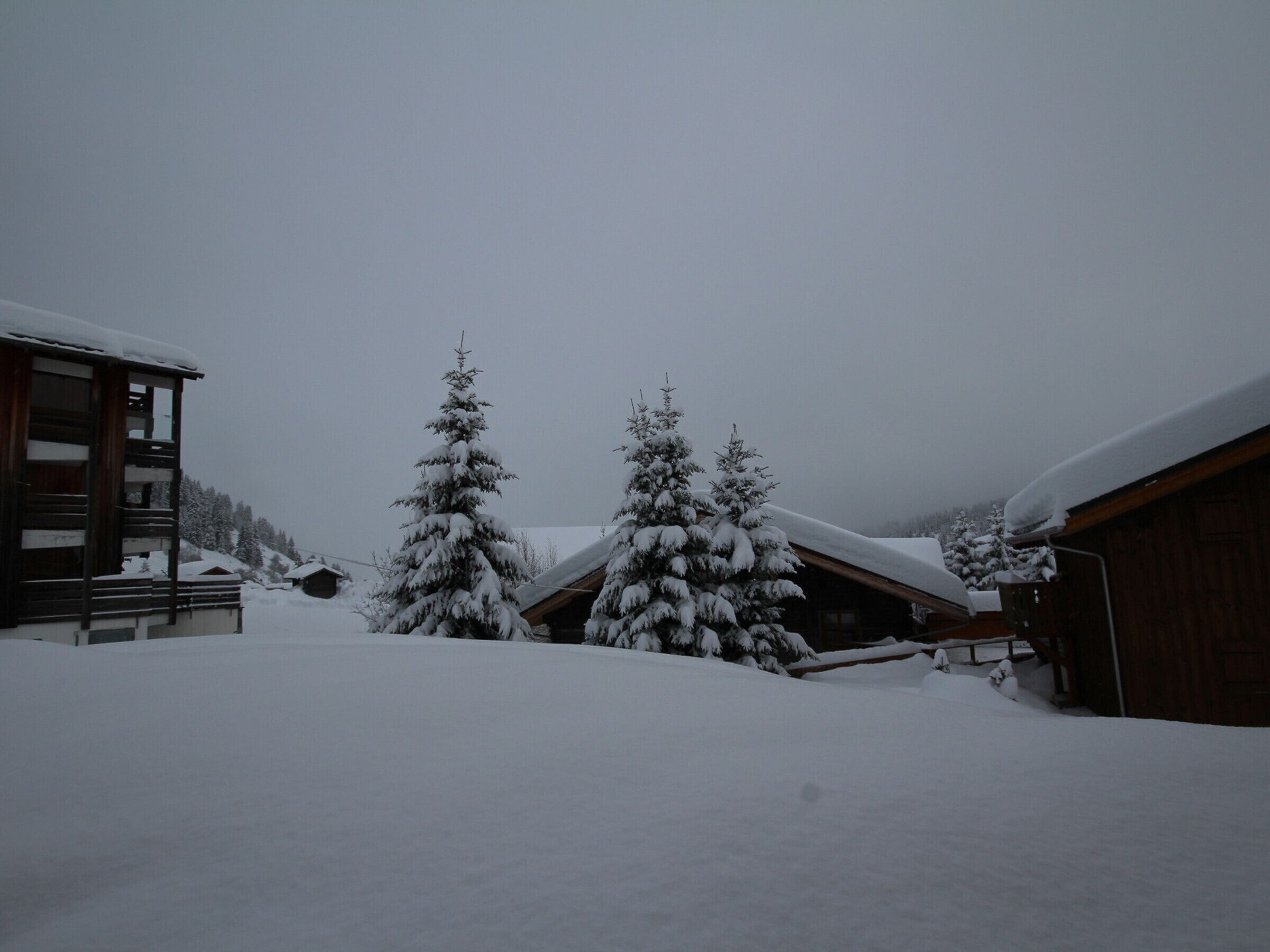 A snow-covered lodge with wooden cabins and snow-laden trees.
