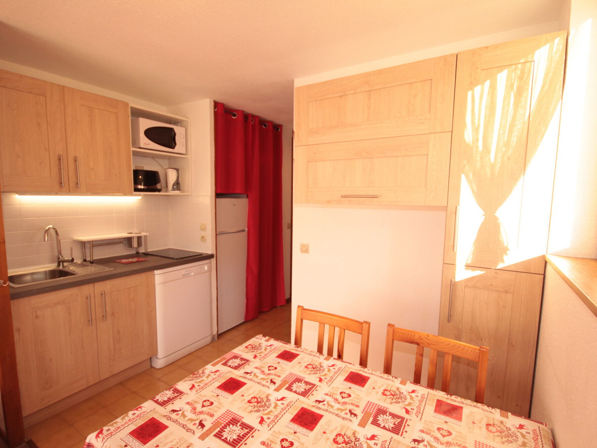 Una cocina compacta con armarios de madera, un microondas, un refrigerador y un lavabo.