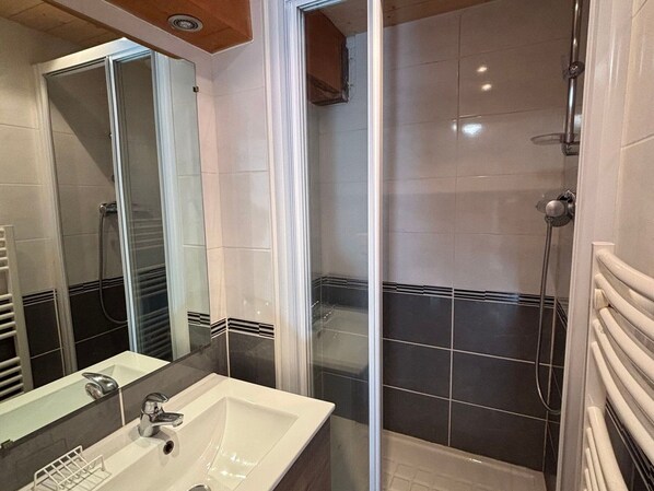 A bathroom with a white sink, a mirror, a shower enclosure, and tiled walls. - 3-room apartment + mezzanine, sleeps 8, pets allowed, near slopes (Peisey-Vallandry)