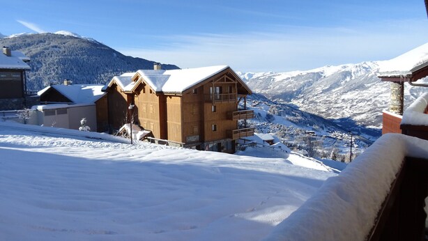 A wooden chalet with a balcony, surrounded by snow-covered mountains and a clear sky. - Charming 4-room apartment, sleeps 8, near slopes, parking, WIFI (Peisey-Vallandry)