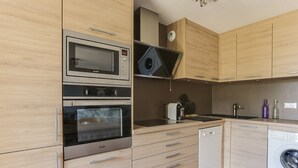 A modern kitchen with stainless steel appliances, wooden cabinets, and a built-in dishwasher. - Charming 4-room apartment, sleeps 8, near slopes, parking, WIFI (Peisey-Vallandry)
