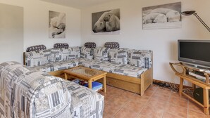 A living room with a sofa, a coffee table, and a television on a wooden stand. - Charming 4-room apartment, sleeps 8, near slopes, parking, WIFI (Peisey-Vallandry)
