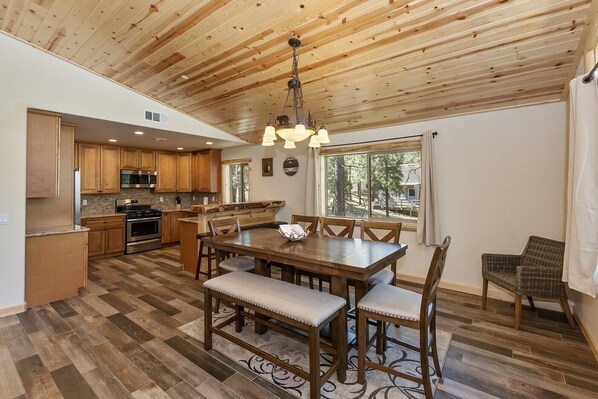 Una cocina amplia con armarios de madera, una isla grande y un comedor con mesa y sillas de madera.