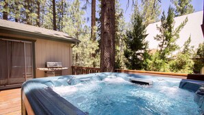 A hot tub on a wooden deck surrounded by trees.