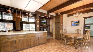 A spacious kitchen with wooden cabinets, a large island, and a dining area with a wooden table and chairs.