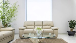 Un salón moderno con un sofá color beige, una mesa de centro de cristal y un ventanal grande.