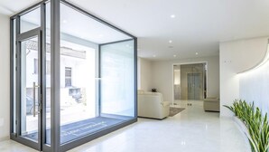 Un moderno vestíbulo de hotel con un separador de vidrio, un sofá blanco y una planta.