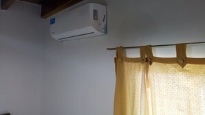 Ein Zimmer mit Deckenventilator, Klimaanlage und Vorhang.