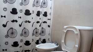 Ein Badezimmer mit Toilette und Bidet, einem gemusterten Duschvorhang und einem kleinen Teppich.