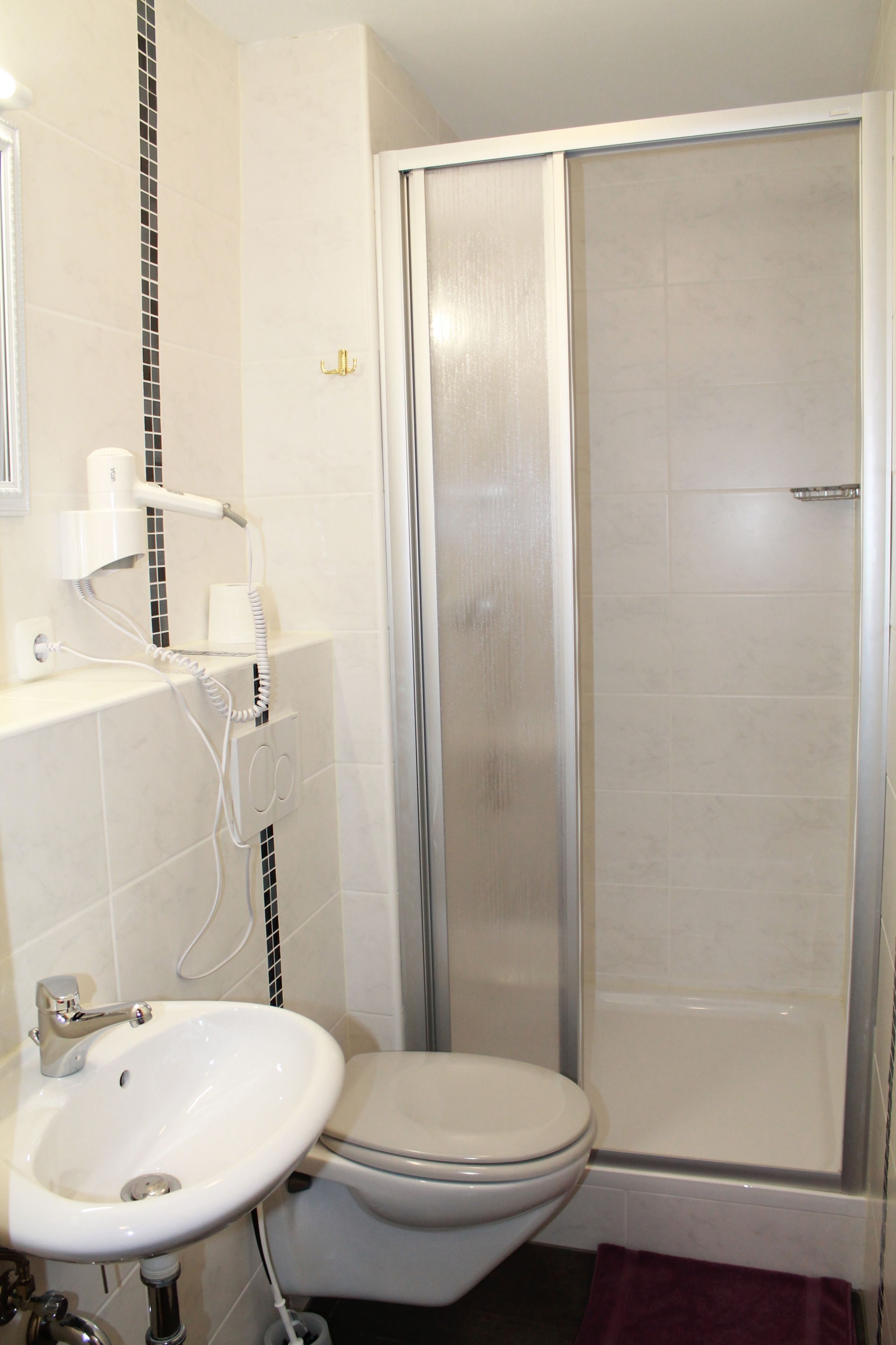 A bathroom with a toilet, sink, and shower.
