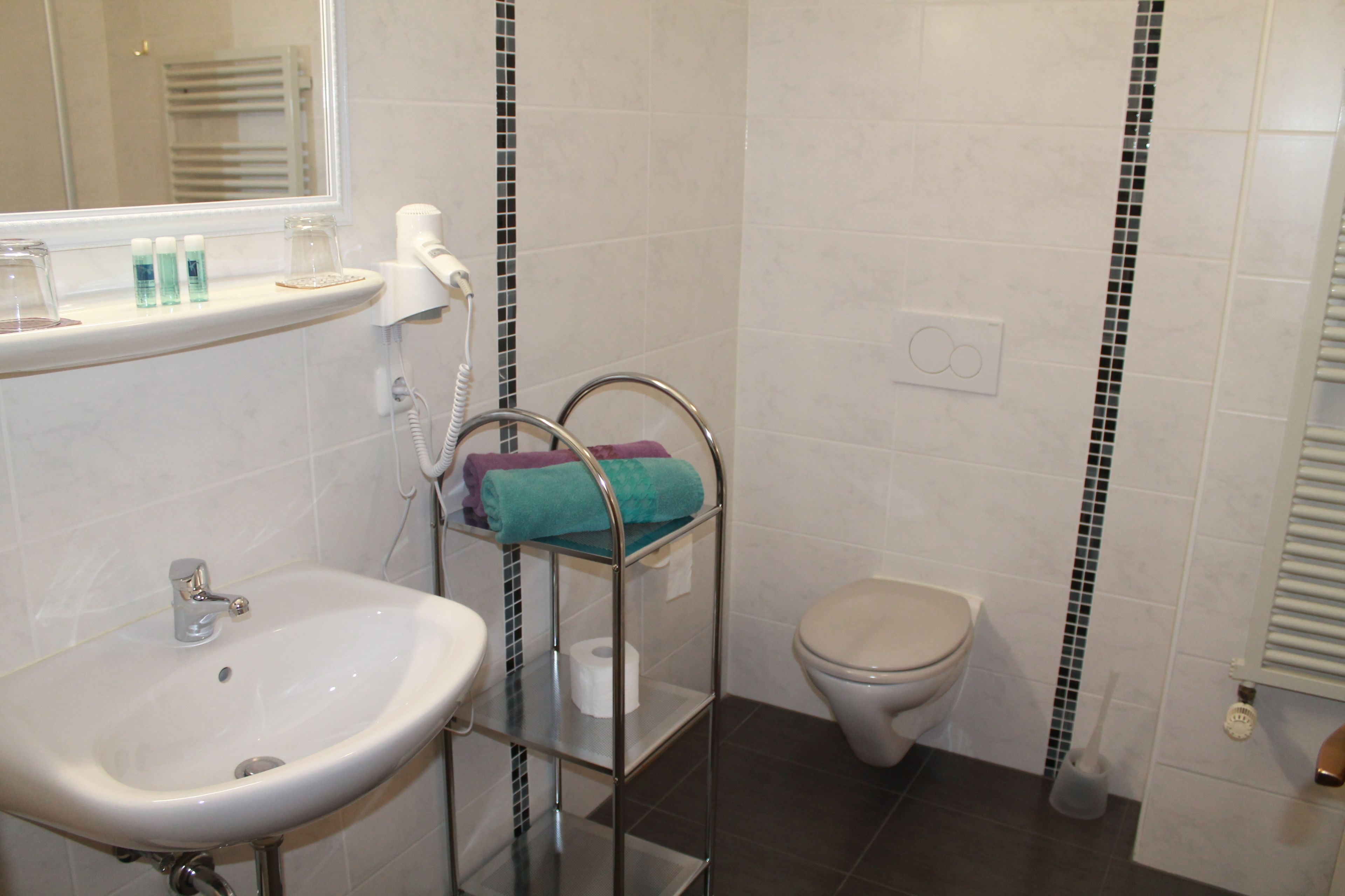 A bathroom with a sink, toilet, and a shelf with towels.