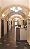 Um saguão de hotel com uma recepção central, teto abobadado e um lustre.