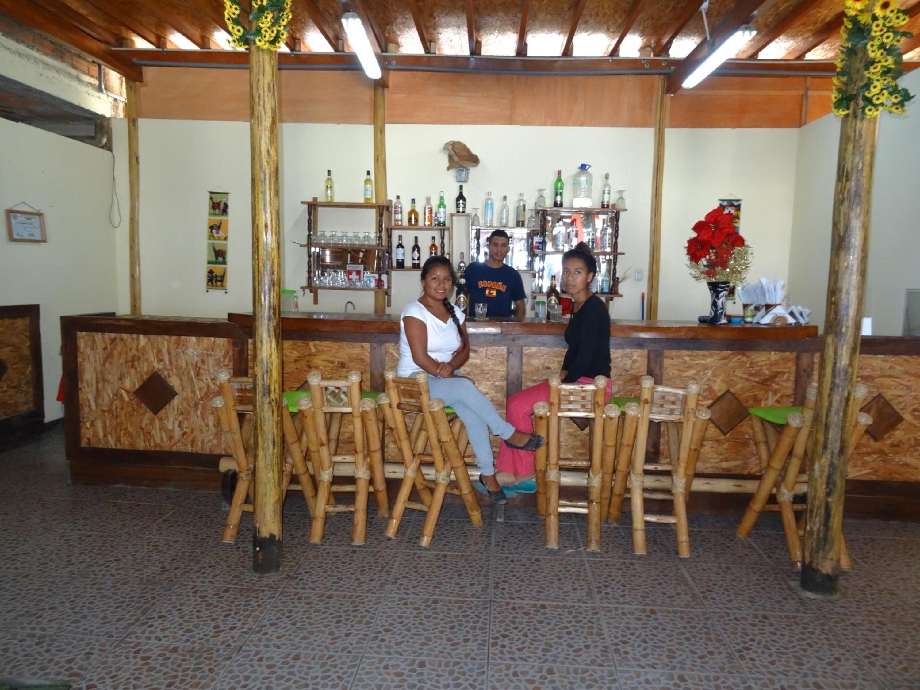Zona de bar con sillas de bambú y una barra con diferentes botellas.