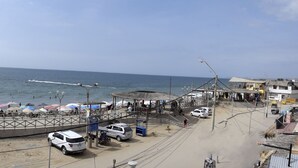 Une promenade en bord de mer avec une plateforme d’observation circulaire, des parasols de plage et une vue dégagée sur la mer.
