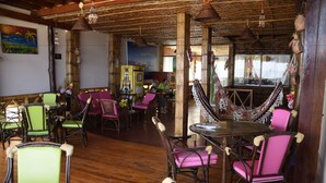 L’intérieur est de style rustique, avec des planchers en bois, des piliers en bambou et un hamac. On y trouve des tables et des chaises recouvertes d’un tissu rose et vert.