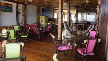 Relax in this tropical retreat with a hammock, chairs, and a large table, surrounded by a high ceiling and large window with a scenic view.