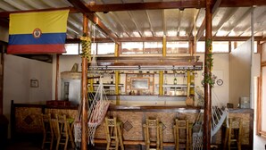 Un espace bar avec des tabourets en bois, un hamac suspendu et un drapeau.