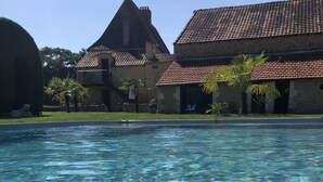 Una piscina cristalina con un edificio de piedra al fondo.