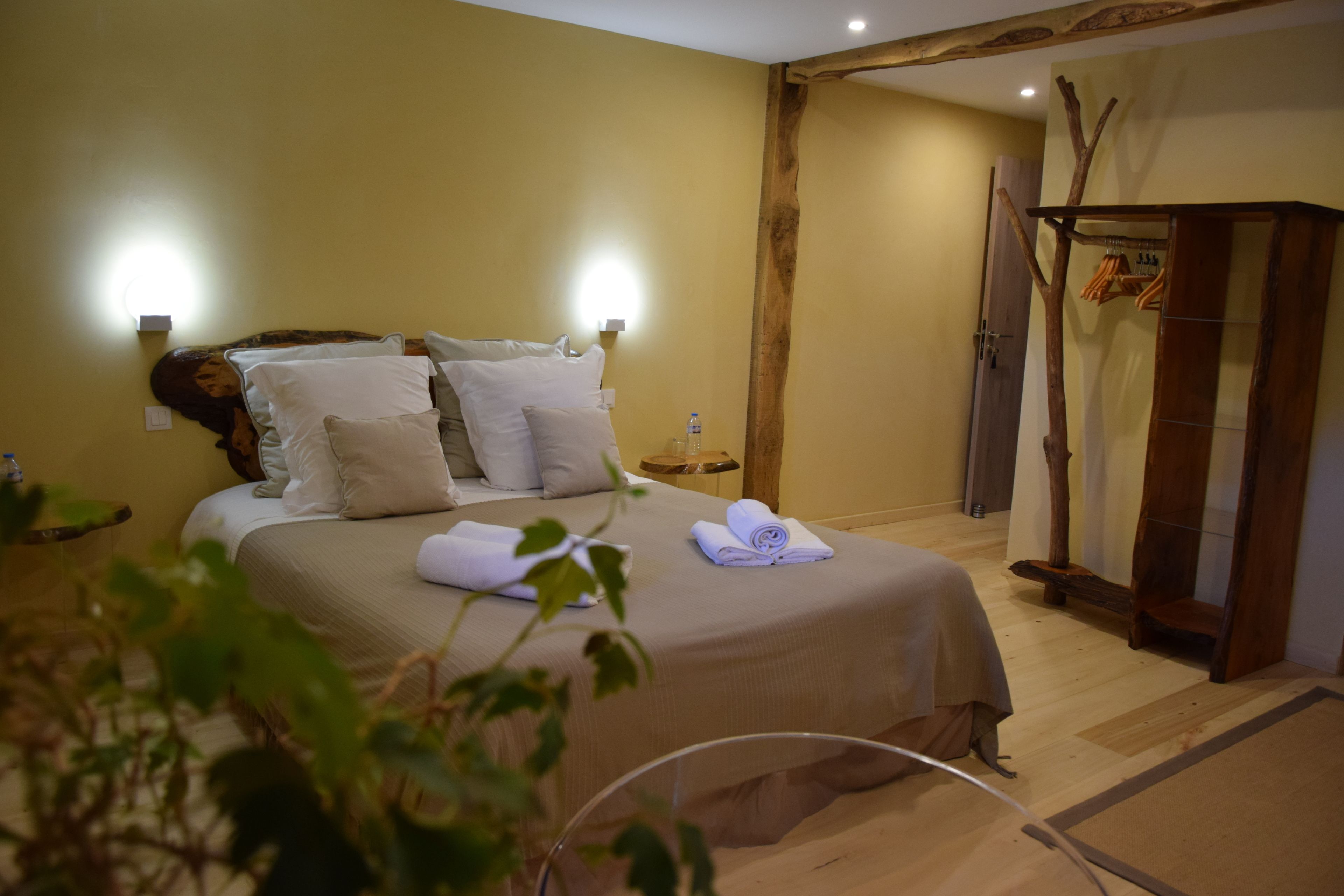 Un dormitorio con cama, almohadas, mesita de noche, botella de agua y armario de madera.