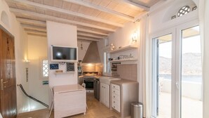 A compact kitchen with a built-in oven, a sink, and a small dining area. - House with character (Tinos)
