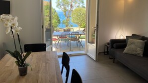 Un salon moderne avec une table à manger en bois, un canapé et une vue sur une terrasse extérieure avec une table et des chaises.