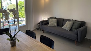 Un salon moderne avec un canapé gris, une table à manger en bois et une plante en pot.