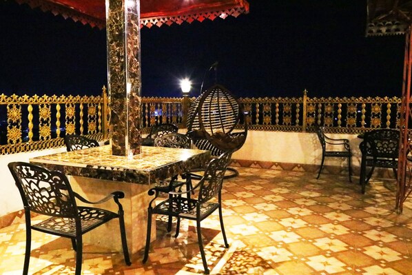 An outdoor seating area with a table and chairs, a decorative hanging light, and a patterned floor.