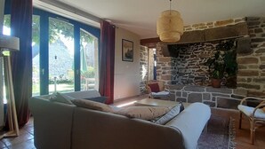 A living room with a stone fireplace, a sofa, a chair, and a TV mounted on the wall.