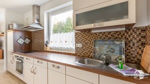 Une cuisine moderne dotée d’un plan de travail en bois, d’un évier en acier inoxydable et d’une fenêtre donnant sur un paysage verdoyant.