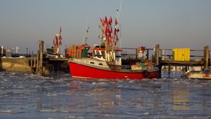 Un bateau rouge était amarré à un quai, et de la glace flottait sur l’eau.