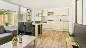 Une cuisine moderne avec un plancher en bois, un coin repas avec une table et des chaises, et un four encastré.