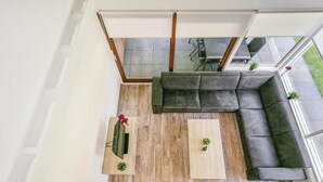 Un salon moderne avec un canapé en cuir foncé, deux tables basses en bois et un téléviseur posé sur un meuble en bois.