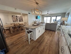 A spacious kitchen with a dining area, a large island, and a living area with a view.